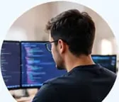 Software engineer working at a desk with code on two monitors